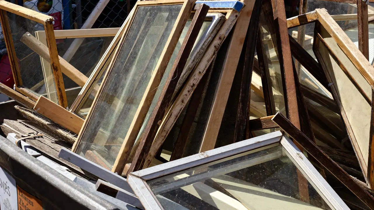 Old window glass panes sorted into a recycling skip on a work site